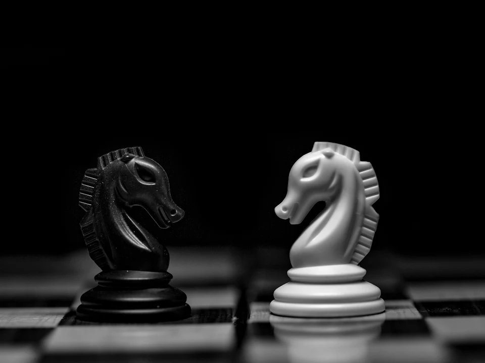 Black and white knights facing each other on a chessboard